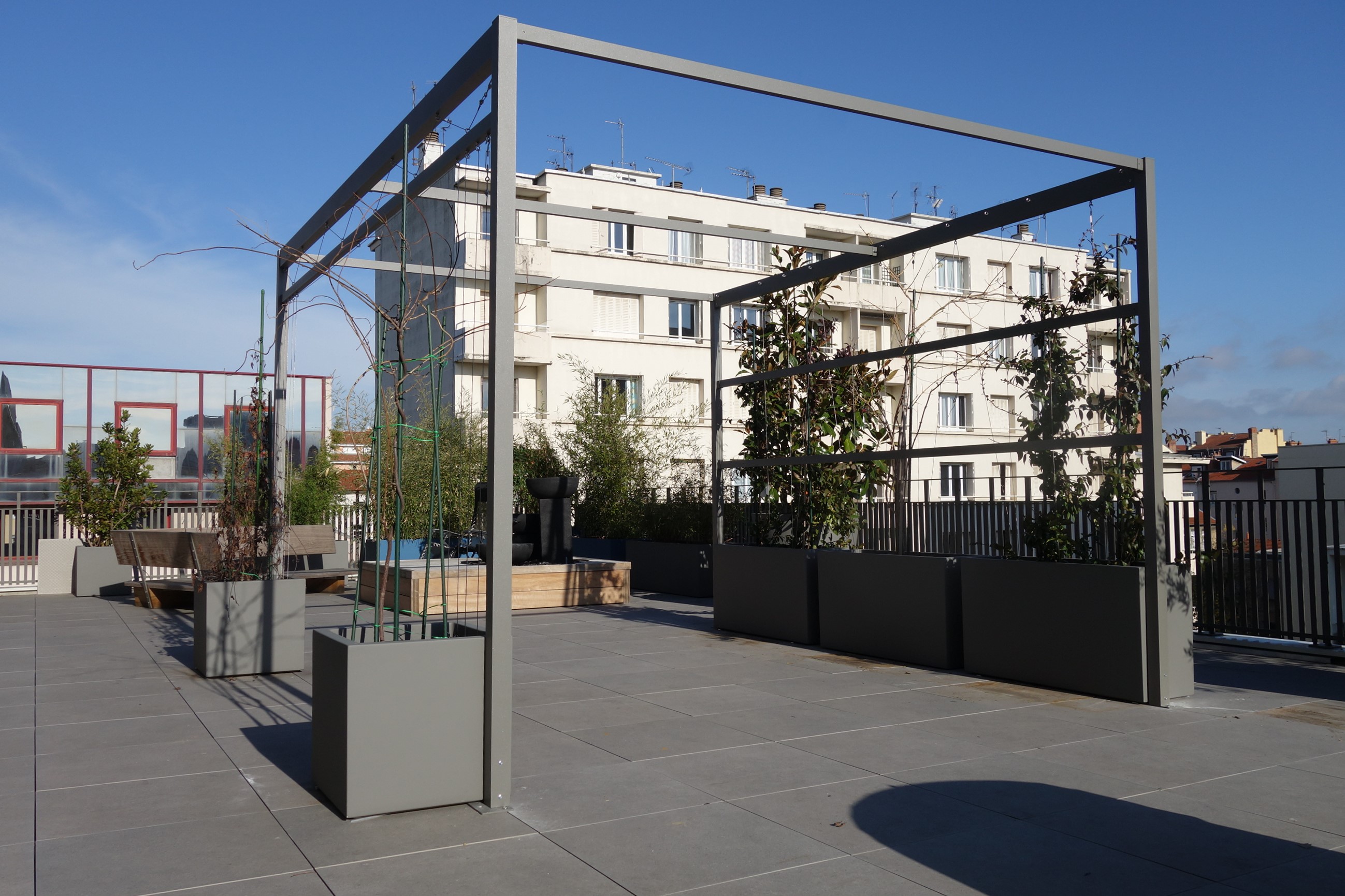 pergola autoportée sur une terrasse sur plots. Les grands bacs lestés assurent la stabilité et la bonne pousse des végétaux.